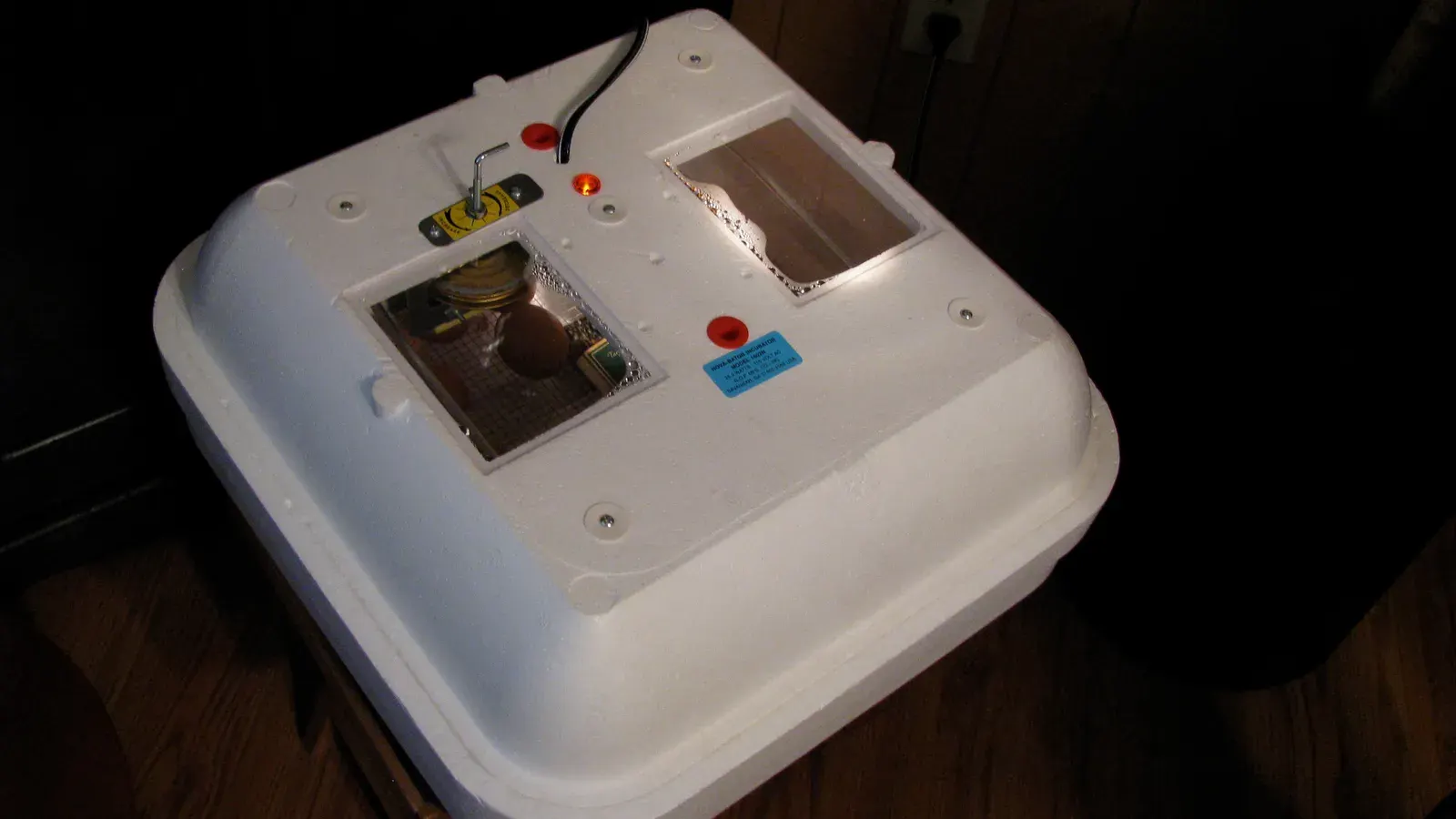 A white tabletop egg incubator with a control panel and viewing window
