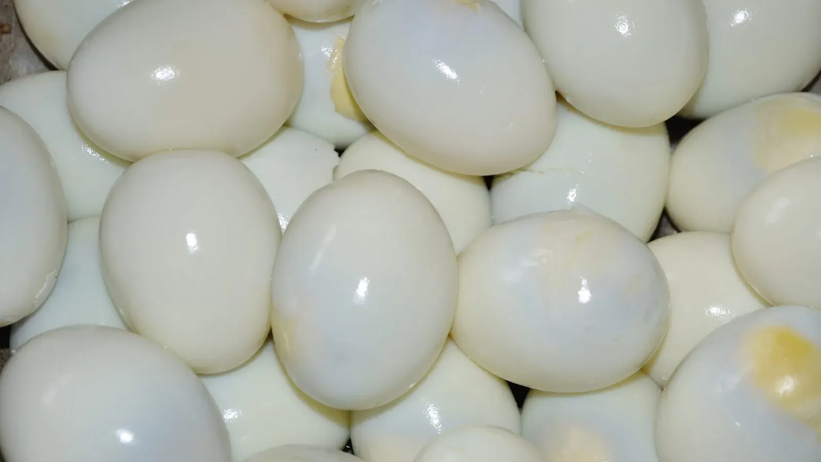 Peeled boiled chicken eggs resting together on a white surface